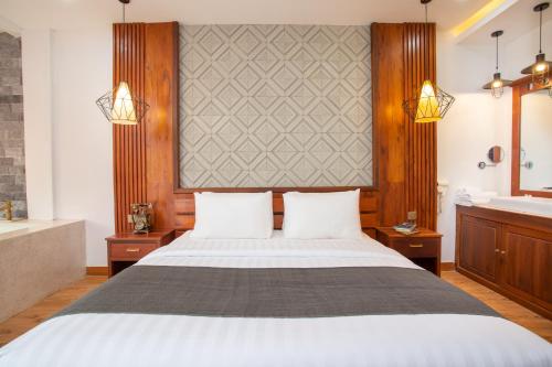 a bedroom with a bed and a tub and a sink at Cambana La Rivière Hotel in Battambang