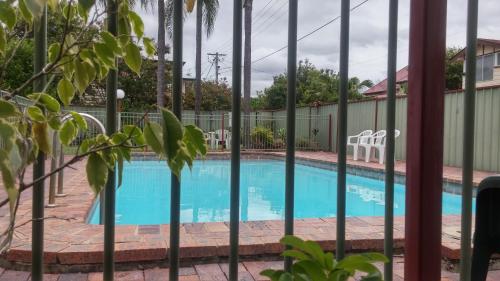 a patio area with a pool and a fence at Motel Monaco in Ipswich