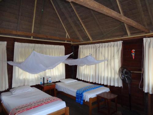 a bedroom with two beds and a mosquito net at Tambopata River in Puerto Maldonado