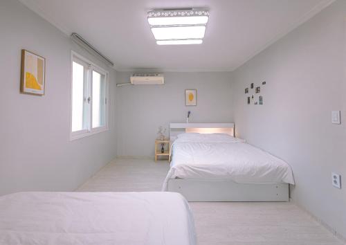 a white bedroom with two beds and a window at 인천 간석동 머니스테이 in Incheon