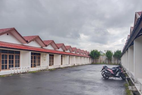 a motorcycle parked in a parking lot next to a building at RedDoorz at Hotel Padjajaran Tasikmalaya in Tasikmalaya