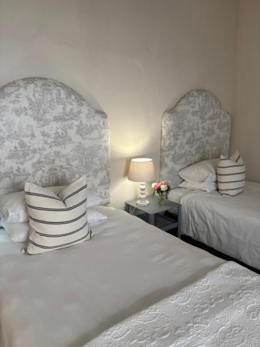 une chambre avec deux lits et une table avec une lampe dans l'établissement Kandelaars Cottage, à Oudtshoorn