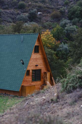 a wooden cabin with a green roof on a hill at Cozy Glamping Cabin With Pool, Perfect For Couples & Families in Arakapas