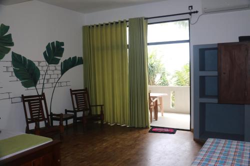 a living room with a green curtain and a table and chairs at Dreamvillage in Dodanduwa