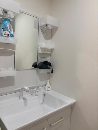 a white bathroom with a sink and a mirror at oni ga shi ma in Osaka