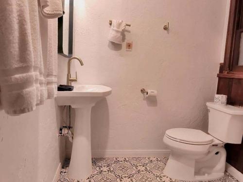 a white bathroom with a toilet and a sink at Three Pines Cabins in Big Bear Lake