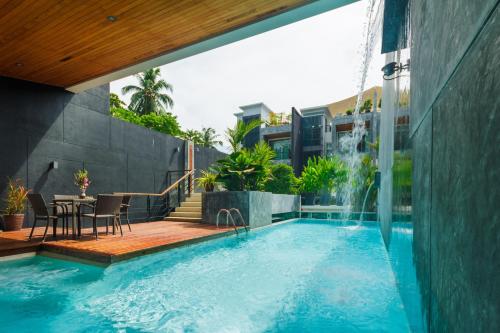 a swimming pool with a table and a fountain at Mojito Residence Phuket in Rawai Beach