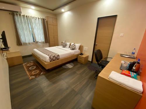 a bedroom with a bed and a desk and a mirror at COSMO STAYS Venus in Pune