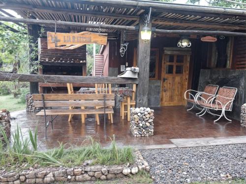 a porch of a house with a bench and chairs at La Rustica in El Durazno