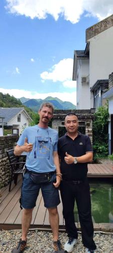 two men standing next to each other on a deck at Yunshan Villa in Huangshan Scenic Area