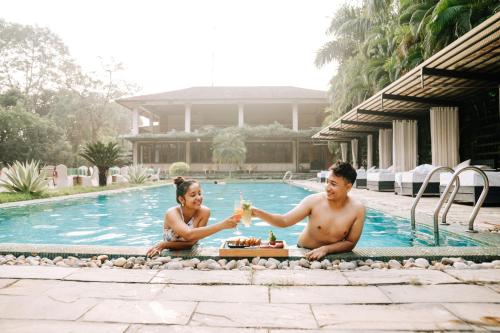 a man and woman sitting in front of a swimming pool at Kasara Chitwan in Chitwan