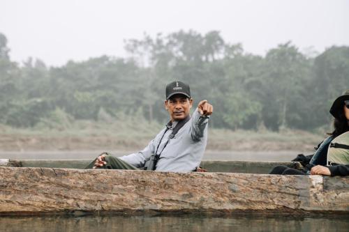 a man sitting in a boat in the water at Kasara Chitwan in Chitwan