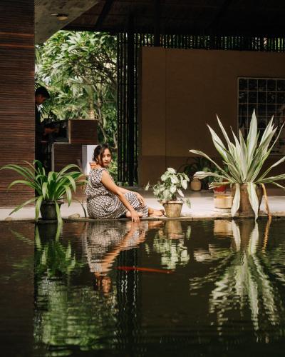 a woman sitting on the ground next to a pool of water at Kasara Chitwan in Chitwan