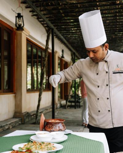 a man in a chefs hat preparing food on a table at Kasara Chitwan in Chitwan
