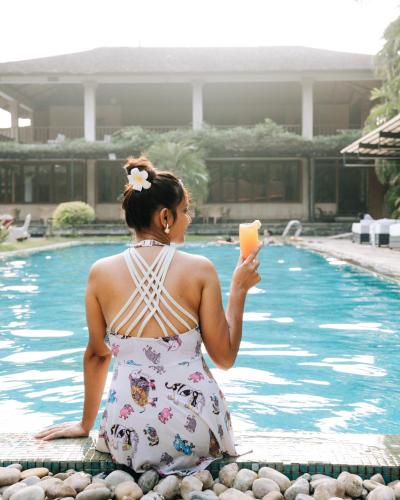 a woman sitting next to a swimming pool holding a piece of food at Kasara Chitwan in Chitwan