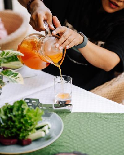 a person pouring a drink into a glass at Kasara Chitwan in Chitwan