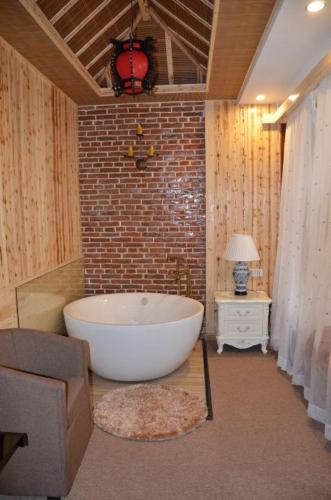 a large white bath tub in a room with a brick wall at Nanxun Luohua Old House Inn in Huzhou