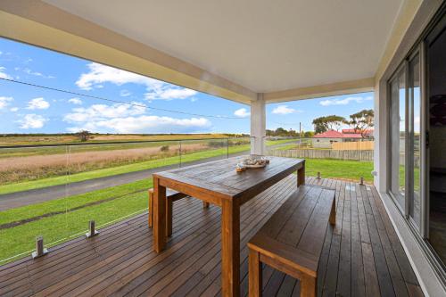 a large screened porch with a table and a view of a field at SEA BREEZE in Narrawong