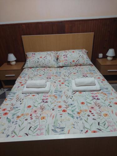 a bed with a floral bedspread and two night stands at Kablar Lazino Brdo in Čačak