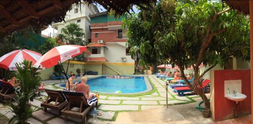 a group of people sitting around a swimming pool at Hotel Thushara in Kovalam