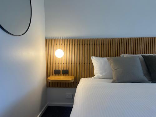 a bedroom with a bed and a light on the wall at South Seas Motel in Merimbula