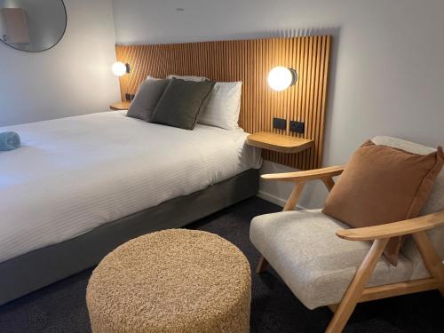 a hotel room with a bed and a chair at South Seas Motel in Merimbula