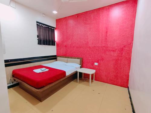 a bedroom with a red wall and a bed with a stool at Malhar Guest House in Pune