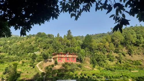 a red house on top of a hill at Ghughuti home stay in Mukteswar