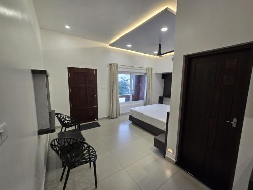 a bedroom with a bed and two chairs and a door at Sea Breeze Cherai Homestay in Pallipuram