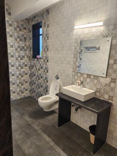 a bathroom with a toilet and a sink and a mirror at Coastal Suites Apart Hotel ---- 8 minutes walk to beach in Benaulim