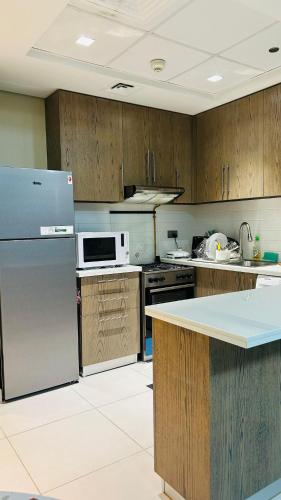 a kitchen with a refrigerator and a microwave at MontRose Residence Tower A in Dubai