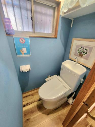 a bathroom with a white toilet in a blue wall at 古民家　鈴乃家～SUZUNOYA　８名まで滞在可　船橋駅の隠れ宿 in Funabashi