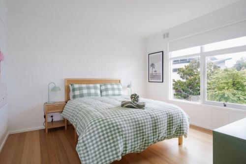 a bedroom with a bed with a plaid blanket and a window at Hamptons on Heales - Classic Beach House Charm in Dromana