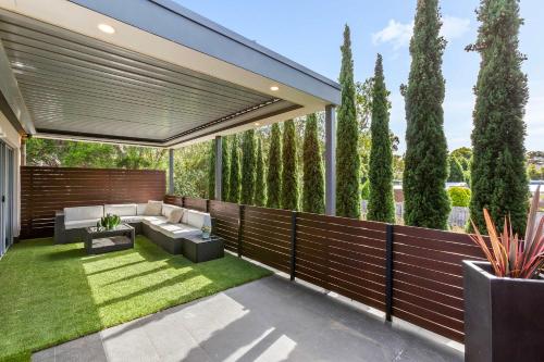 a patio with a fence with a couch and grass at Stylish getaway near beach with stunning sunsets in Saint Leonards