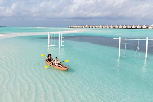 2 persone in kayak in acqua su una spiaggia di LUX* South Ari Atoll Resort & Villas a Maamigili