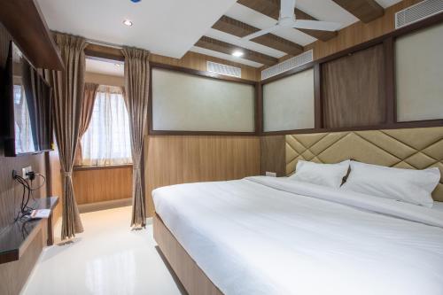 a bedroom with a large white bed and a window at Hotel PRM Aruna Archadia in Erode