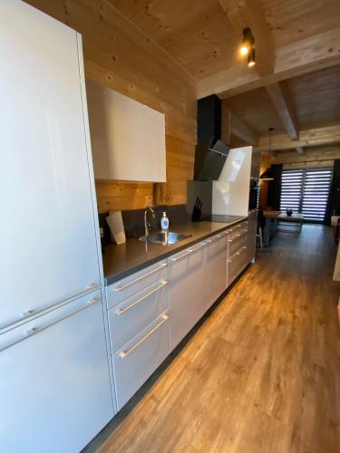 a kitchen with a white refrigerator and a wooden floor at Nassfeld Holiday Home in Rattendorf
