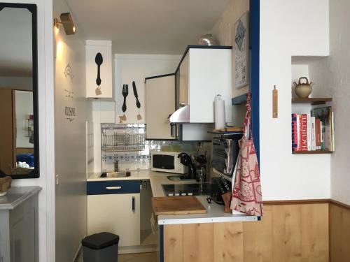 une petite cuisine avec des armoires blanches et un évier dans l'établissement STUDIO SUR PISTES direct face rassemblement écoles de skis classé 3 Etoiles 4 Couchages COSY, à Saint-Lary-Soulan