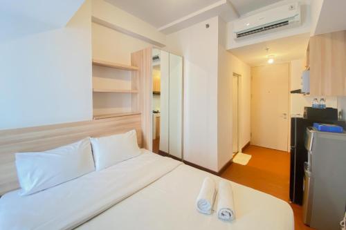 RawalembangModern Look Studio at Tokyo Riverside PIK 2 Apartment By Travelio的卧室配有白色的床和2拖鞋