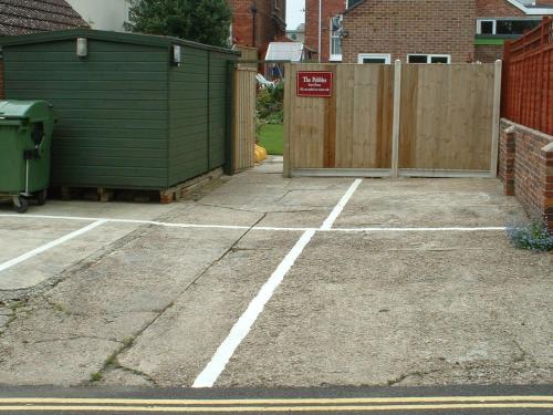 un parking vide avec un bâtiment et une clôture dans l'établissement The Pebbles - Adults Only, à Weymouth