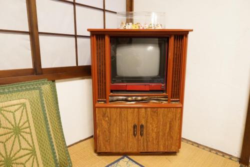 a small tv in a wooden cabinet in a room at Lodging House NAO in Aomori