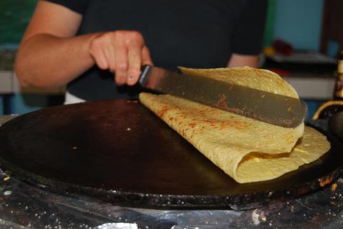 a person cutting a sandwich with a knife on a pan at Amber Lagoon Backpackers Lodge in Vleirivier