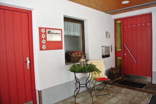 a hallway with red doors and a table with a plant at Haus Christopherus in Klösterle am Arlberg
