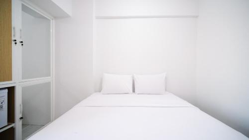 a bedroom with a white bed with two pillows at Best Choice and Comfy Studio Apartment at Suncity Residence By Travelio in Sidoarjo