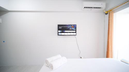 a bedroom with a white bed and a tv on the wall at Best Choice and Comfy Studio Apartment at Suncity Residence By Travelio in Sidoarjo