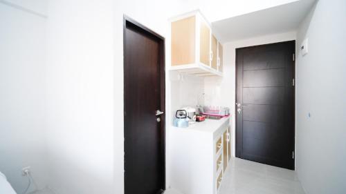 a kitchen with a white counter and a black door at Best Choice and Comfy Studio Apartment at Suncity Residence By Travelio in Sidoarjo