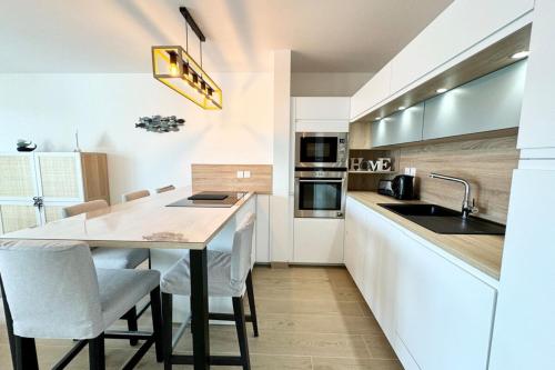 une cuisine avec une table, des chaises et un évier dans l'établissement T3 de standing Plein bourg - 100m des plages, à Saint-Pierre-Quiberon