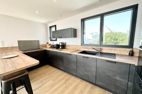 d'une cuisine avec des placards noirs, un évier et une fenêtre. dans l'établissement Luxury ! Contemporaine neuve Vue imprenable 180, à Ploemeur