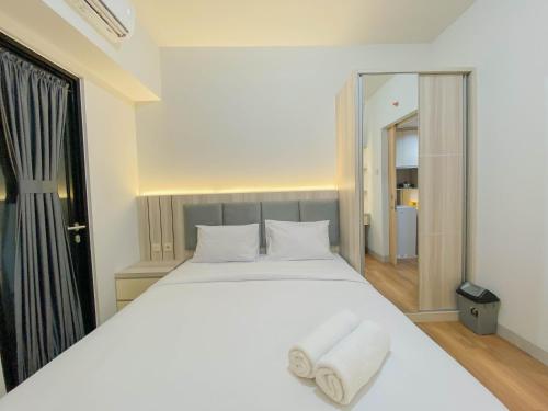 a bedroom with a large white bed with towels on it at Fully Furnished 1BR The Alton Apartment By Travelio in Semarang