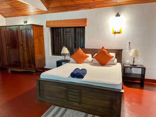 ein Schlafzimmer mit einem großen Bett mit orangefarbenen Kissen in der Unterkunft Elmwon Heritage in Matara